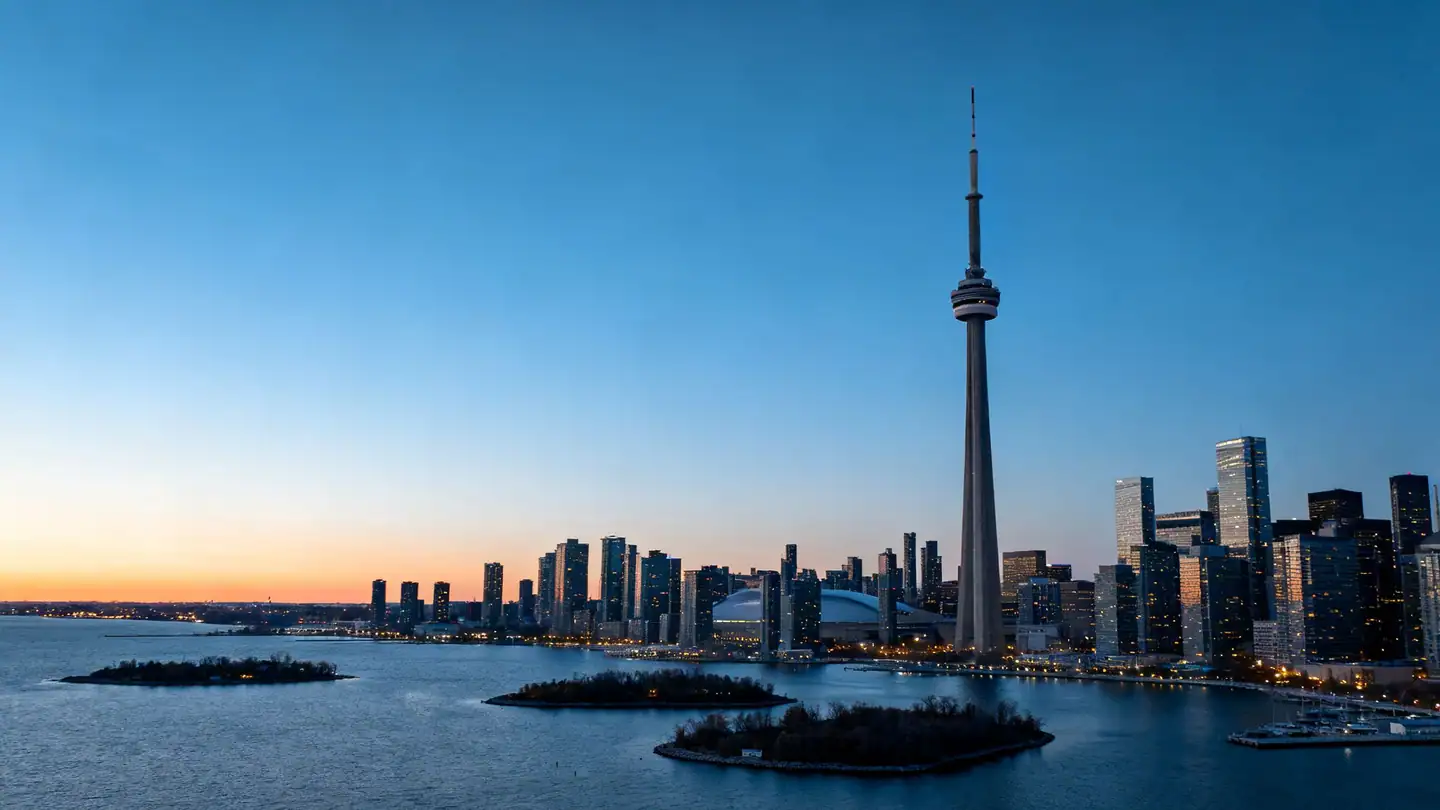 The Toronto skyline across Lake Ontario with its tall concrete communications tower and harbour islands at dusk