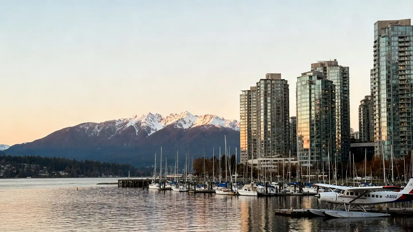 Vancouver, British Columbia: a dense skyline of slim glass residential towers across Coal Harbour at sunset